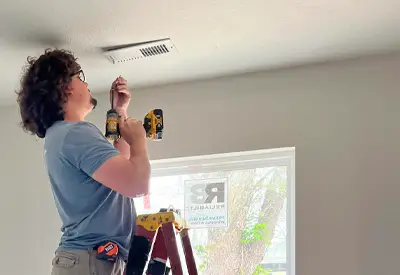 Service Technician Logan installing HVAC vents in ceiling